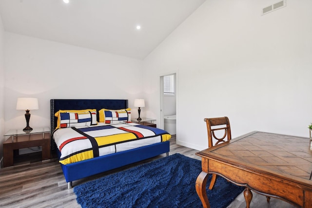 bedroom featuring ensuite bath, high vaulted ceiling, and wood-type flooring