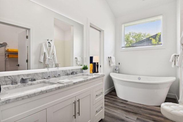 bathroom with a bath, vanity, hardwood / wood-style flooring, and lofted ceiling