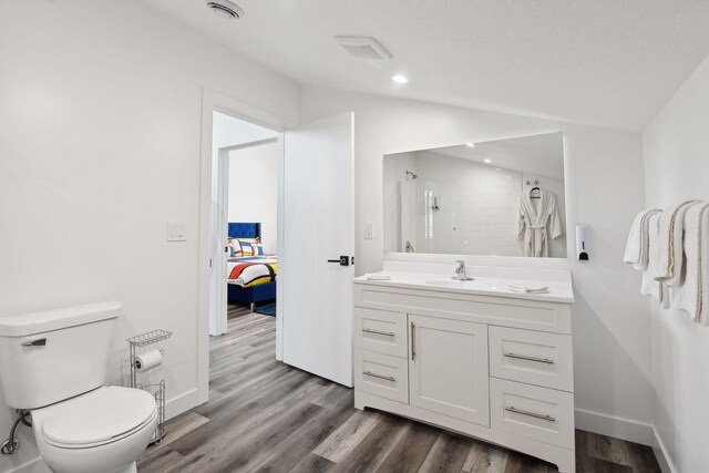 bathroom featuring walk in shower, vanity, vaulted ceiling, wood-type flooring, and toilet