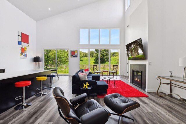 living room with bar, a tile fireplace, a towering ceiling, and wood-type flooring