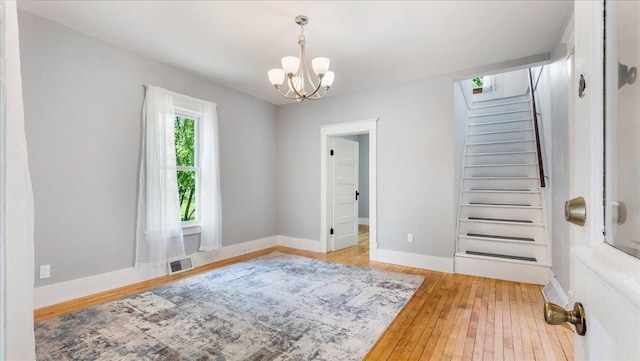 unfurnished room featuring light hardwood / wood-style floors and an inviting chandelier