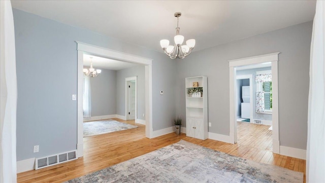 empty room featuring hardwood / wood-style flooring and a chandelier