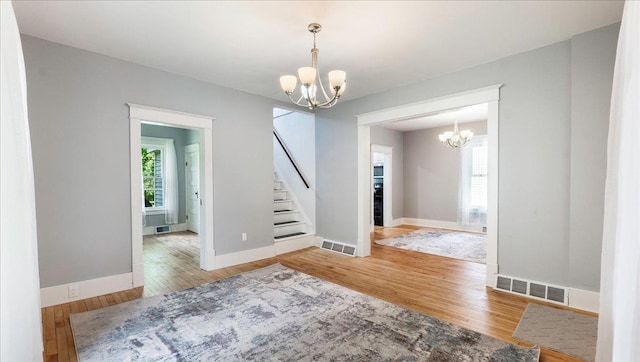 spare room with hardwood / wood-style floors and an inviting chandelier