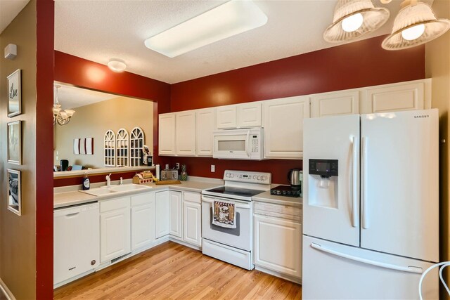 kitchen with light hardwood / wood-style floors, white cabinetry, white appliances, decorative light fixtures, and sink