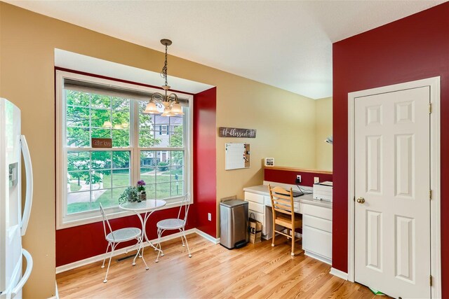 office space with a wealth of natural light, light wood-type flooring, and an inviting chandelier