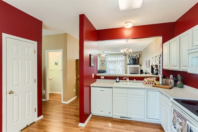 kitchen featuring light hardwood / wood-style flooring, hanging light fixtures, white cabinetry, sink, and white appliances