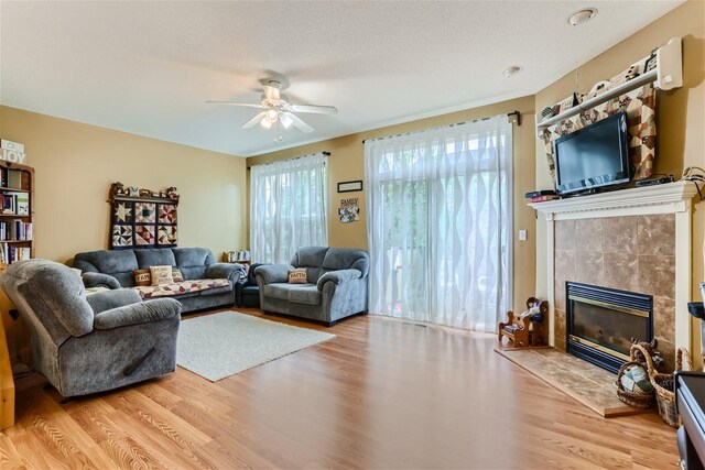 living room featuring a fireplace, ceiling fan, and light hardwood / wood-style flooring