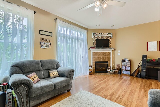 living room featuring ceiling fan, light wood-type flooring, and a fireplace