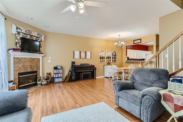 living room with a fireplace, ceiling fan with notable chandelier, and hardwood / wood-style floors