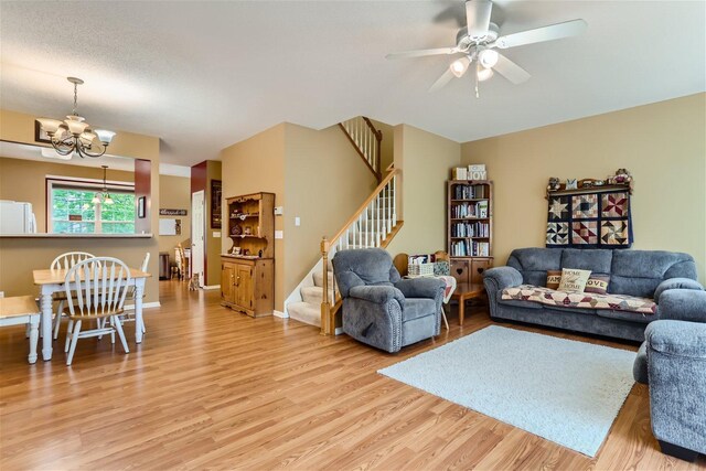 living room featuring light hardwood / wood-style flooring and ceiling fan with notable chandelier