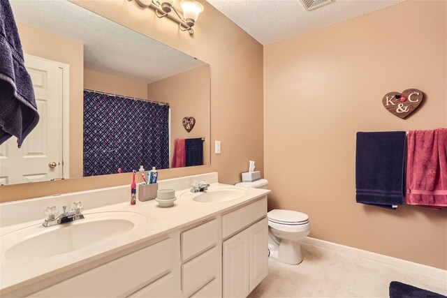 bathroom with double vanity, tile flooring, toilet, and a textured ceiling