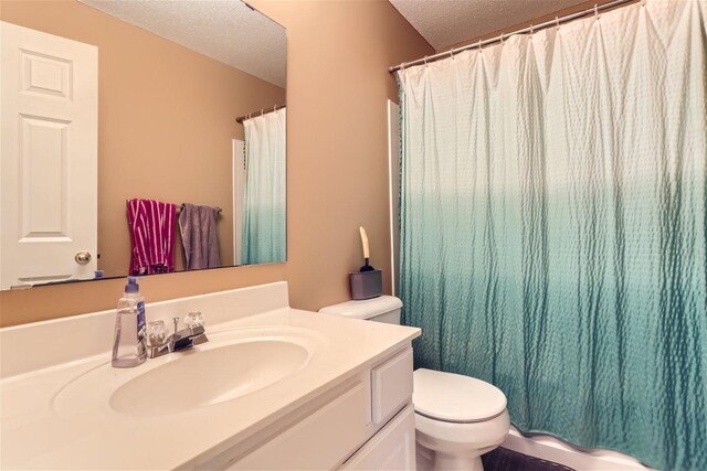 bathroom with vanity with extensive cabinet space, a textured ceiling, and toilet