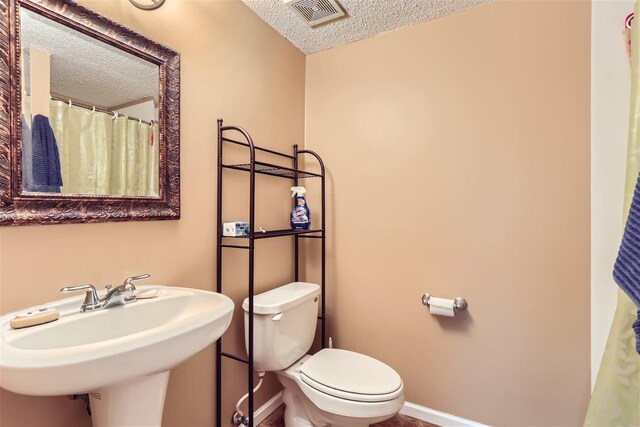 bathroom featuring sink, a textured ceiling, and toilet