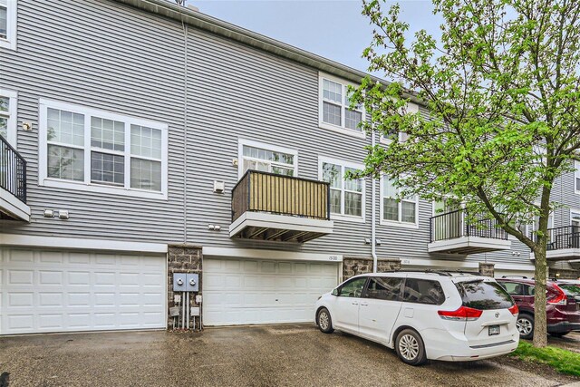 rear view of property featuring a garage and a balcony