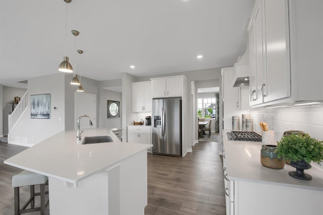 kitchen with pendant lighting, a center island with sink, sink, stainless steel refrigerator with ice dispenser, and white cabinetry