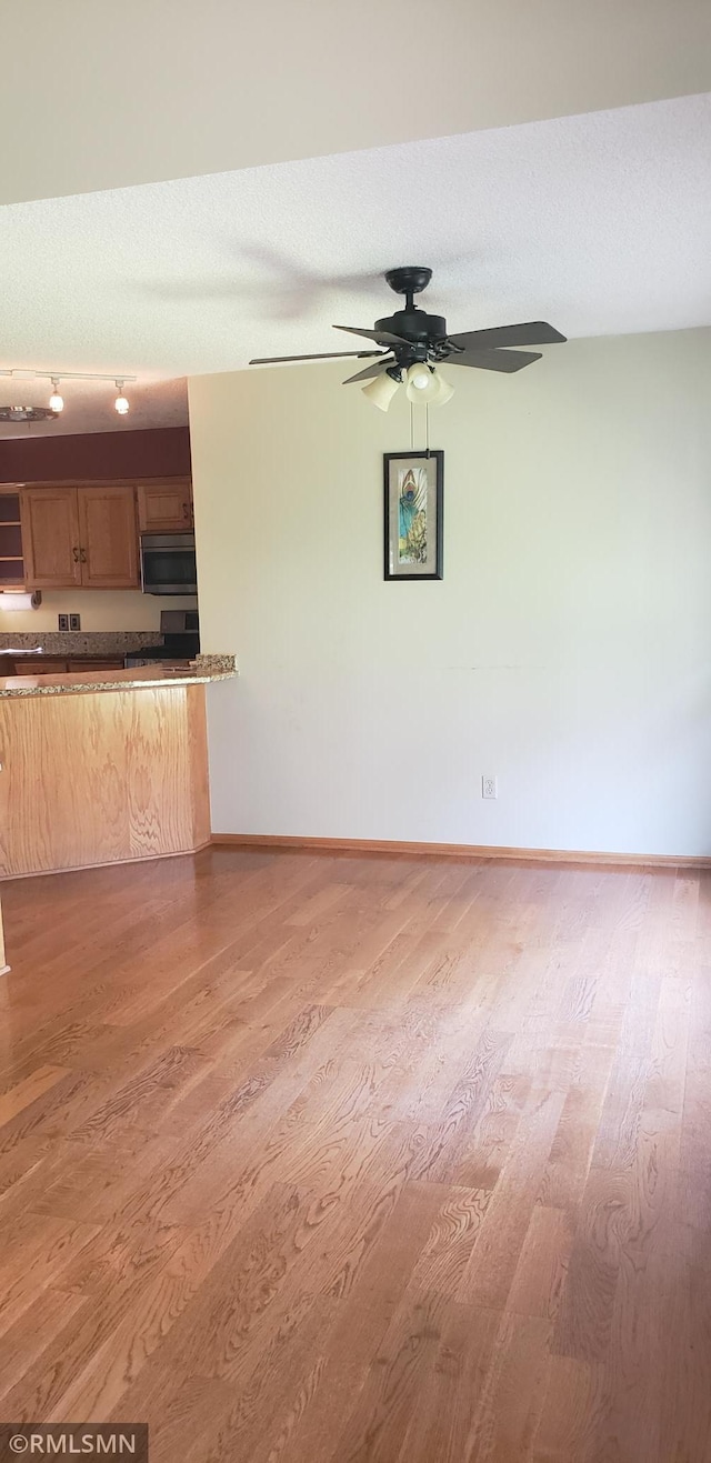 unfurnished living room featuring ceiling fan, hardwood / wood-style floors, and a textured ceiling