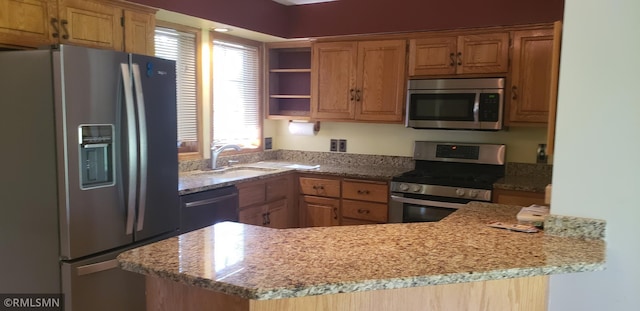 kitchen featuring light stone counters, appliances with stainless steel finishes, kitchen peninsula, and sink