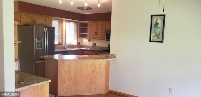 kitchen with sink, a textured ceiling, kitchen peninsula, stone counters, and stainless steel appliances