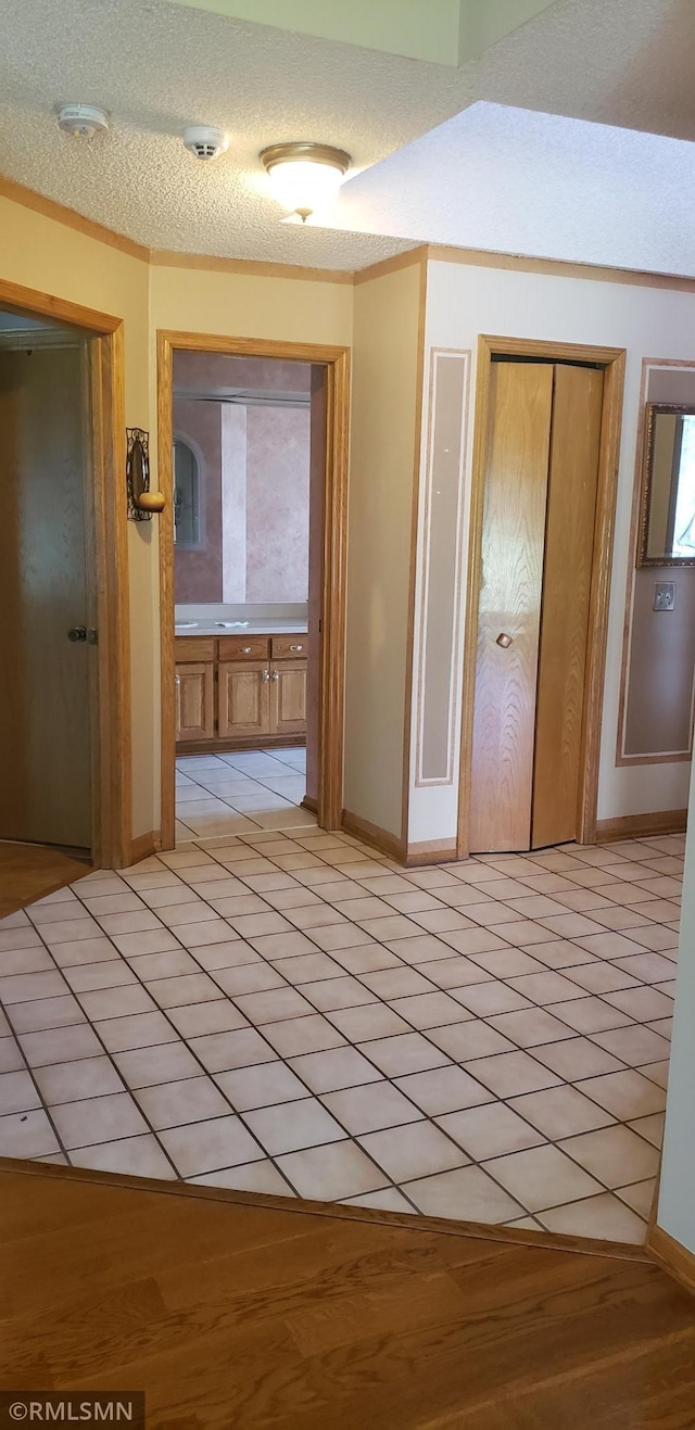 corridor featuring light tile patterned flooring and a textured ceiling