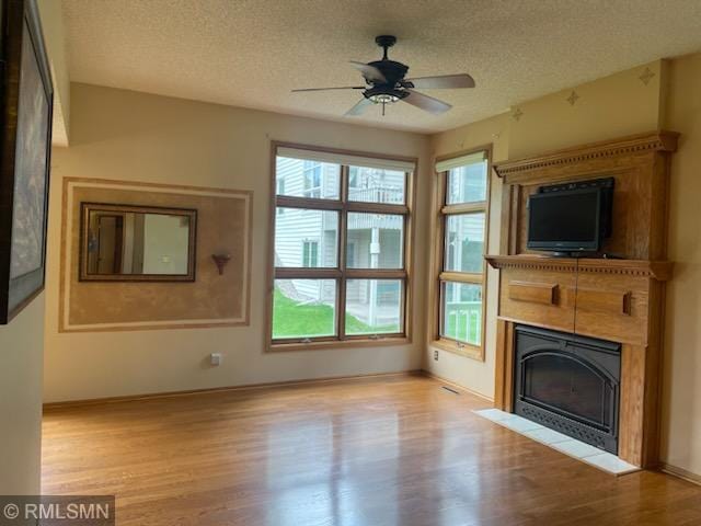 unfurnished living room with ceiling fan, light hardwood / wood-style floors, and a textured ceiling