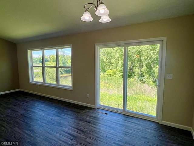 interior space with a chandelier, a wealth of natural light, and dark wood-type flooring