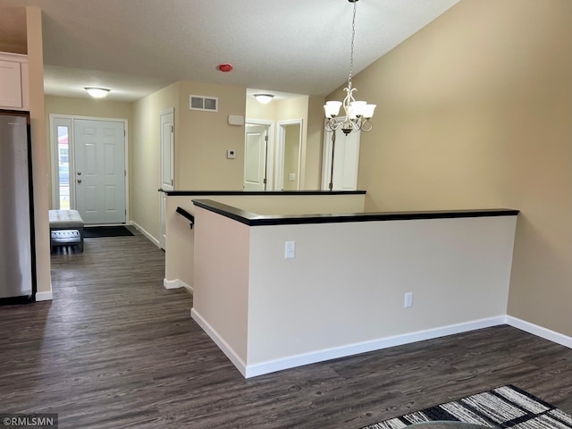 kitchen featuring dark hardwood / wood-style flooring, pendant lighting, an inviting chandelier, white cabinetry, and stainless steel refrigerator