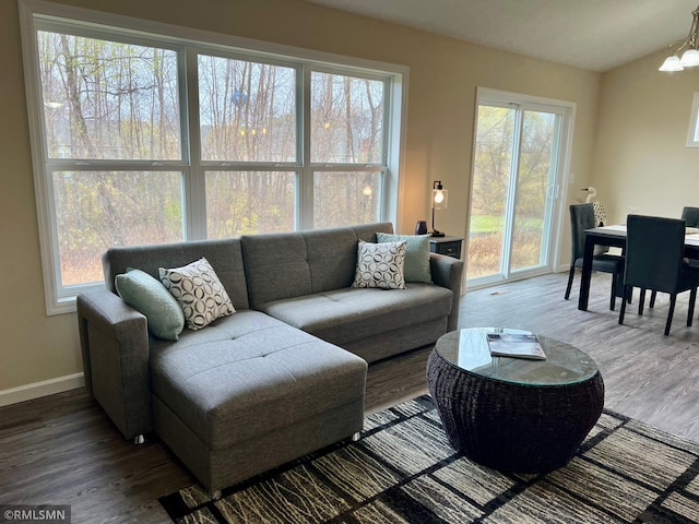 living room with a wealth of natural light, hardwood / wood-style floors, and a notable chandelier