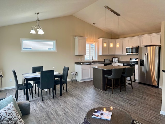 kitchen featuring lofted ceiling, sink, hanging light fixtures, dark hardwood / wood-style floors, and stainless steel appliances