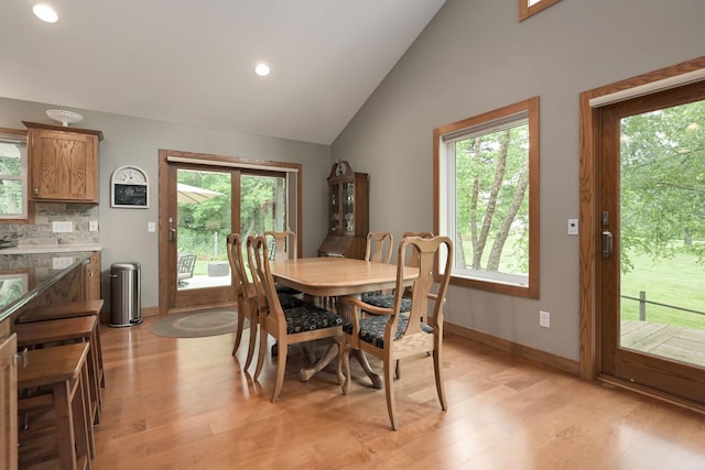 dining room featuring lofted ceiling, light wood-type flooring, and a wealth of natural light