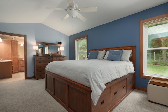 bedroom featuring ceiling fan, ensuite bathroom, light carpet, and lofted ceiling