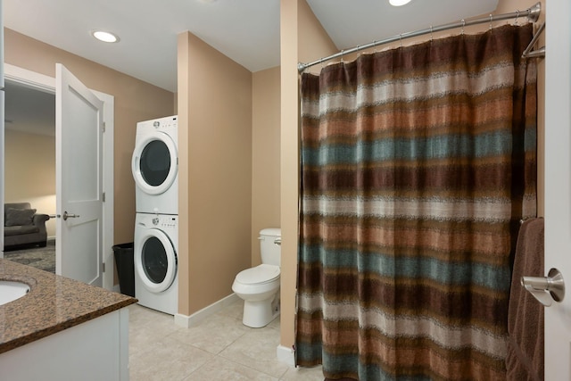 bathroom with toilet, vanity, stacked washer and dryer, and tile patterned flooring