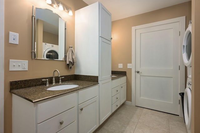 bathroom featuring stacked washer and clothes dryer, tile patterned floors, and vanity