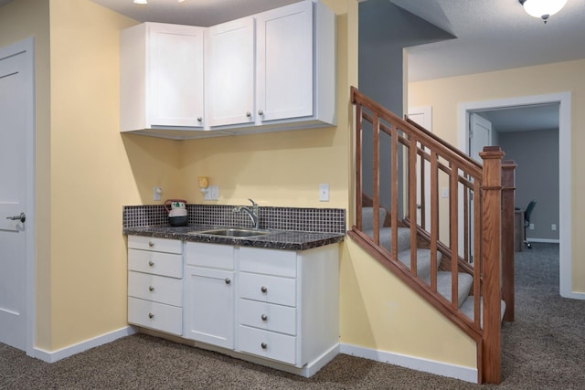 kitchen featuring dark colored carpet, white cabinets, and sink