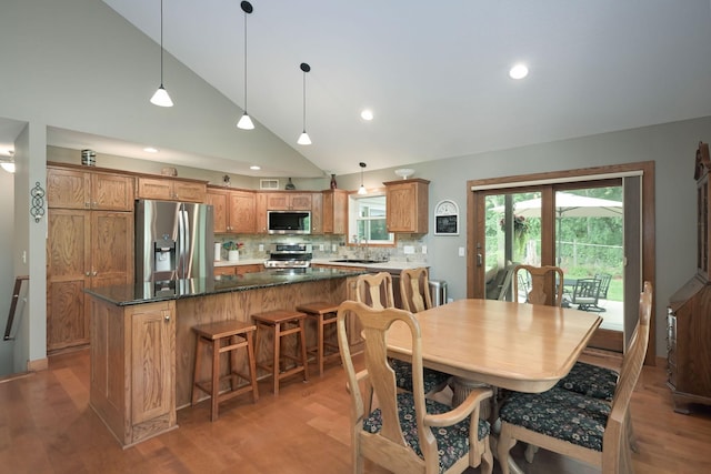 dining space with high vaulted ceiling, sink, and hardwood / wood-style flooring