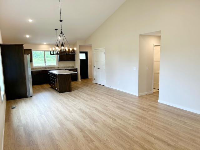 kitchen featuring decorative light fixtures, a kitchen island, dark brown cabinetry, light hardwood / wood-style flooring, and stainless steel fridge