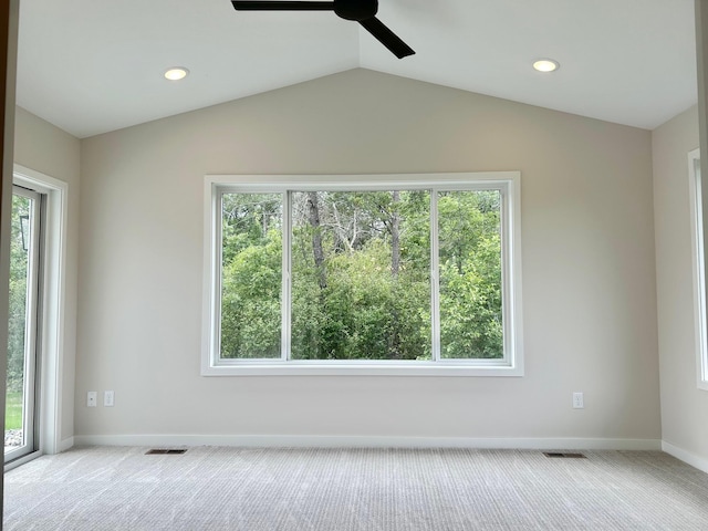 carpeted spare room featuring lofted ceiling, a healthy amount of sunlight, and ceiling fan