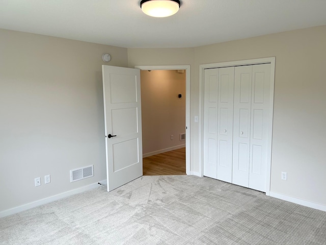 unfurnished bedroom with light colored carpet and a closet