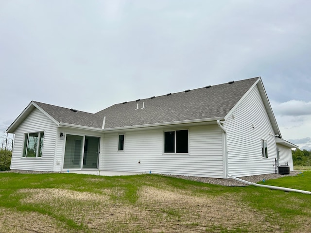 rear view of property with central AC unit, a lawn, and a patio