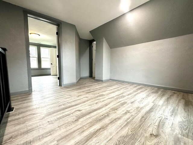 additional living space with lofted ceiling and light hardwood / wood-style flooring