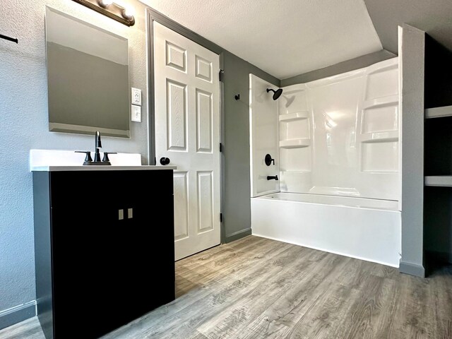 bathroom featuring shower / bathtub combination, a textured ceiling, wood-type flooring, and vanity