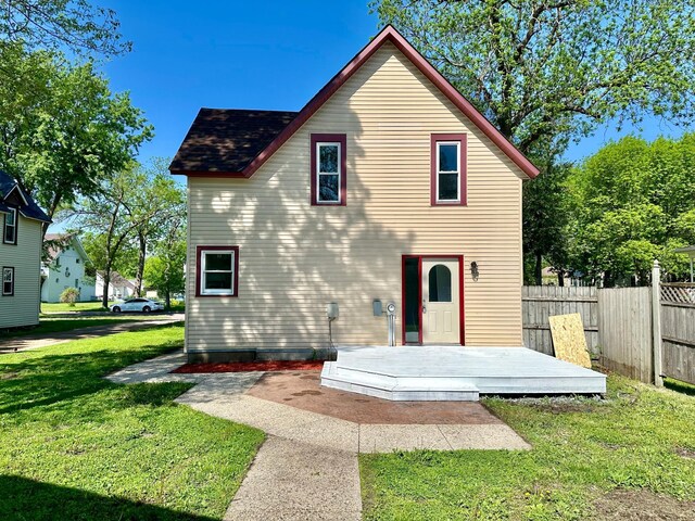 back of property with a wooden deck and a lawn