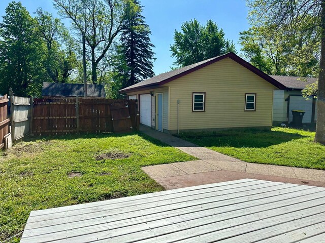 rear view of house featuring a garage, a deck, and a lawn