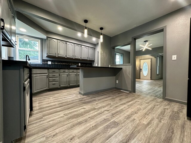 kitchen featuring light hardwood / wood-style flooring, tasteful backsplash, hanging light fixtures, and gray cabinets