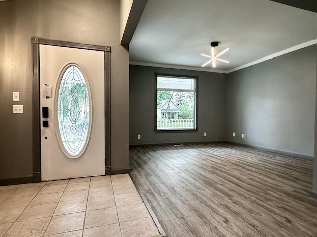 entrance foyer with ornamental molding, a healthy amount of sunlight, and light hardwood / wood-style floors