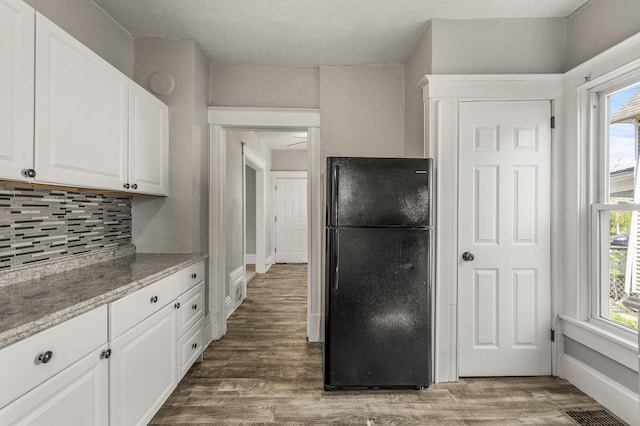 2806 Aldrich Ave N, Minneapolis, MN 55411 - kitchen featuring freestanding refrigerator, tasteful backsplash, white cabinetry, wood finished floors, and light stone counters