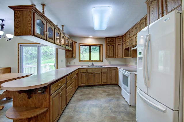 kitchen with light tile patterned flooring, white appliances, sink, exhaust hood, and kitchen peninsula