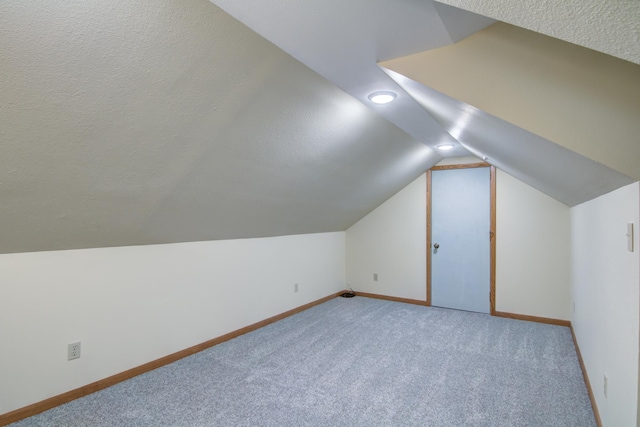 bonus room with a textured ceiling, lofted ceiling, and light colored carpet