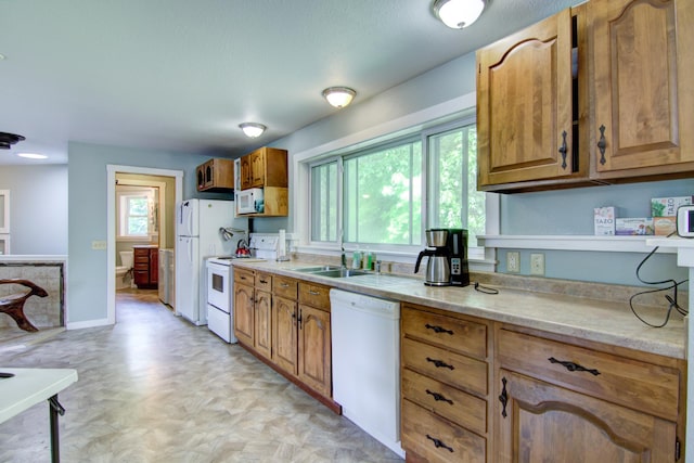 kitchen featuring light tile patterned flooring, sink, white appliances, and a wealth of natural light