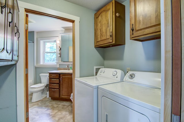 washroom with light tile patterned flooring, sink, washing machine and dryer, and a textured ceiling