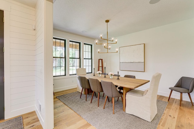 dining room with a textured ceiling, light wood-type flooring, and a chandelier